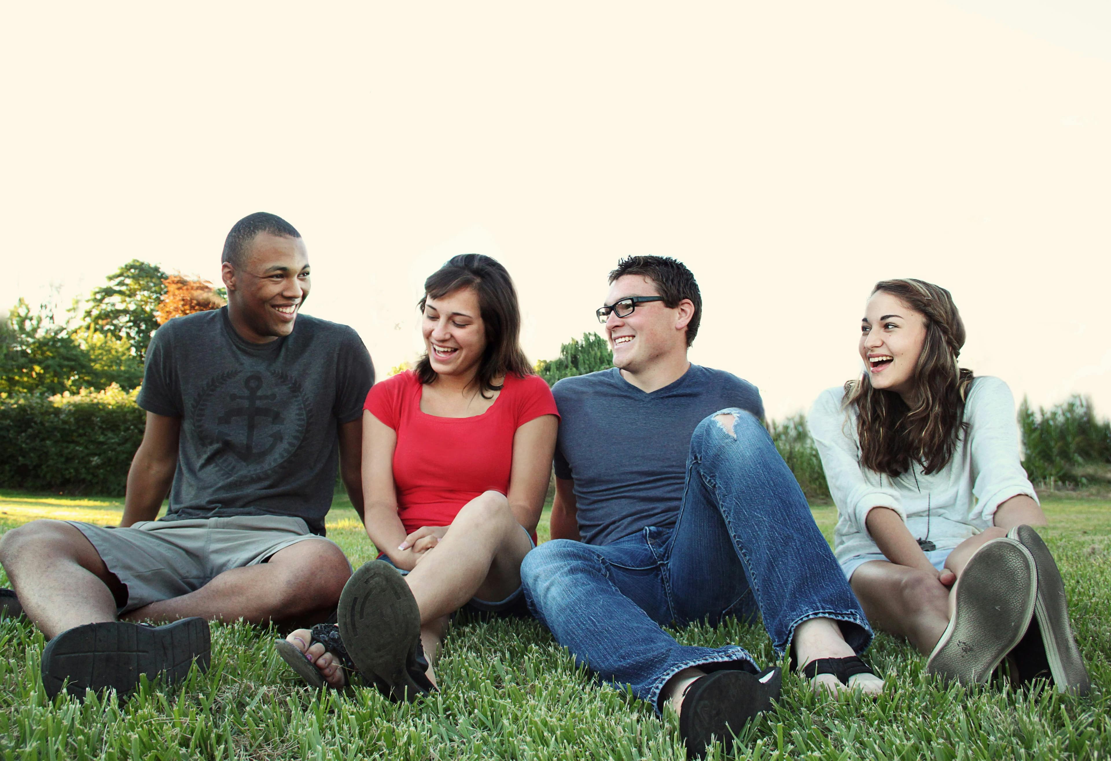 Four friends sitting together on grass